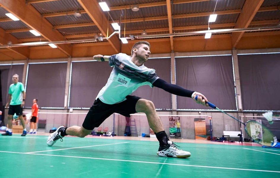 Na zdjęciu znajduje się mężczyzna bez jednego przedramienia, który gra w badmintona.