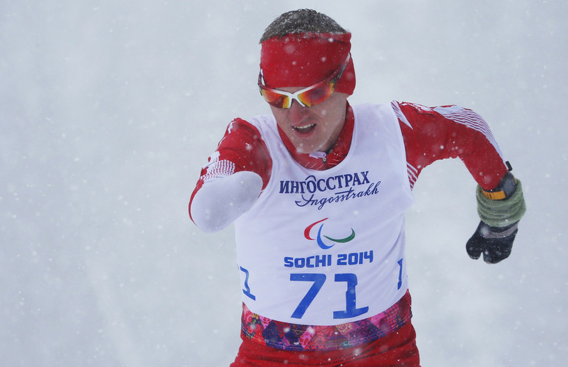 Zdjęcie przedstawia mężczyznę w sportowym stroju, który biegnie w śniegu.