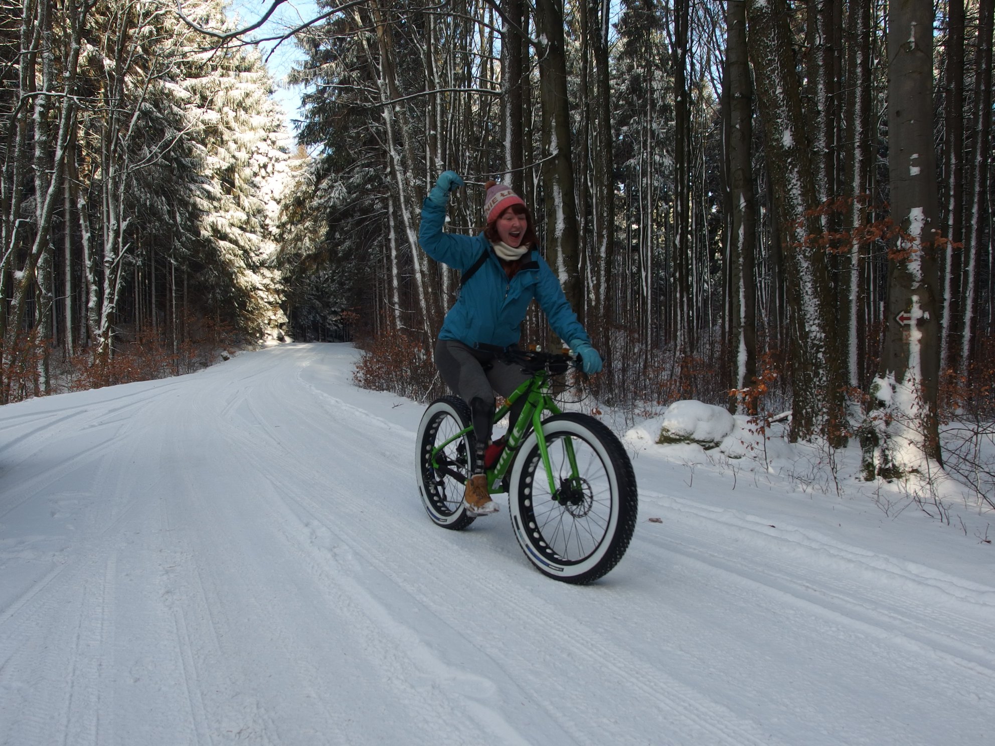 Na zdjęciu znajduje się Kaśka Maciąg, która jedzie na rowerze po zaśnieżonej drodze.