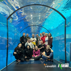 Zdjęcie wszystkich uczestników, instruktorów i osób obecnych podczas wydarzenia, w specjalnym tunelu znajdującym się wewnątrz basenu, z którego można obserwować osoby podczas nurkowania.